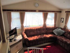 a living room with a brown leather couch and a desk at Golden Sands: Richmond GS:- 6 berth, Blow heated, Access to the beach in Ingoldmells