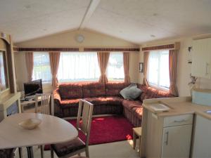 a living room with a couch and a table at Golden Sands: Richmond GS:- 6 berth, Blow heated, Access to the beach in Ingoldmells