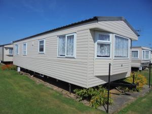 a white tiny house sitting in a yard at Golden Sands: Richmond GS:- 6 berth, Blow heated, Access to the beach in Ingoldmells