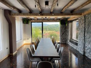 une grande table et des chaises dans une chambre avec une grande fenêtre dans l'établissement Вила Дружинци, 
