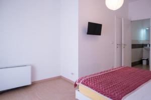 a white bedroom with a bed and a tv at Ca' Popolo Venice in Mestre
