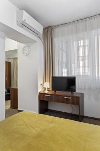1 dormitorio con 1 cama y escritorio con TV en Lina Hotel, en Bucarest