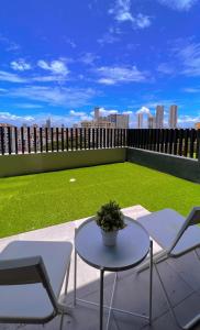 um pátio com uma mesa e cadeiras e um campo verde em 2BR Georgetown Luxury Suite #RoofTopPool #Beacon em George Town