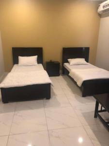 two beds in a room with white sheets and pillows at Hotel La Orilla Muzaffarabad in Muzaffarabad