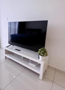 een flatscreen-tv op een witte stand met een potplant bij 2BR Georgetown Luxury Suite #RoofTopPool #Beacon in George Town