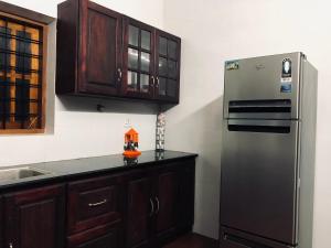 a kitchen with a black refrigerator and wooden cabinets at Garuda Suites in Varkala