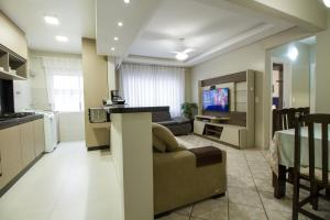 a kitchen and living room with a couch and a television at Apto Germano Praia in Balneário Camboriú