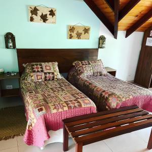 a room with two beds and a bench in it at La Araucaria VGB in Villa General Belgrano