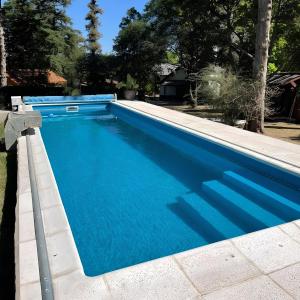 a swimming pool with blue water in a yard at La Araucaria VGB in Villa General Belgrano