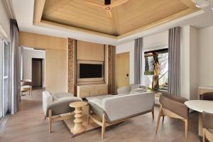 a living room with a couch and chairs and a tv at Coorg Marriott Resort & Spa in Madikeri