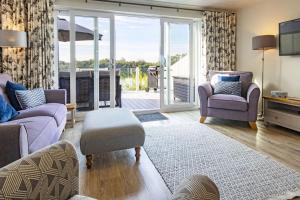 ein Wohnzimmer mit einem Sofa und Stühlen sowie einem Balkon in der Unterkunft Spring Lake 14, Lakeside Retreat in South Cerney