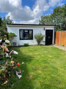 een klein wit huis met een tuin bij Newly built Large garden ensuite guest studio in Borehamwood