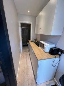 a small kitchen with a counter top with a microwave at Newly built Large garden ensuite guest studio in Borehamwood