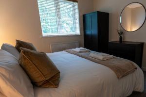 een slaapkamer met een wit bed met 2 kussens en een spiegel bij Elms House, sleeps 5, free parking in Reading