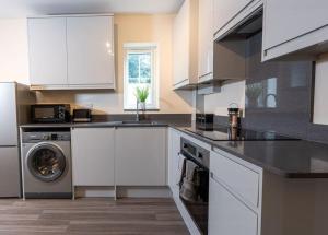 cocina con armarios blancos y lavavajillas en Elms House, sleeps 5, free parking en Reading