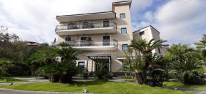 un bâtiment blanc avec des palmiers devant lui dans l'établissement Hotel Tiro a Volo, à Pouzzoles