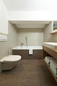 a bathroom with a tub and a toilet and a sink at Hotel am Hof in Sölden