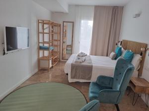 um quarto com uma cama, uma cadeira e uma televisão em Bamblue Boutique Apartments em Pineda de Mar