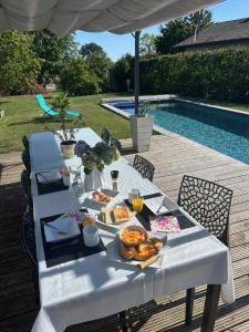 uma mesa branca com comida ao lado de uma piscina em la petite bulle em Montagnat