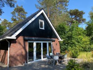 a house with a black roof and a table and chairs at Luxe Vakantiehuis Vosje op de Veluwe Nunspeet in Nunspeet