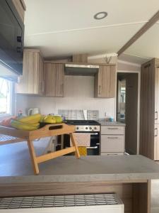 a kitchen with a wooden table with bananas on it at Modern Family Caravan with WiFi at Valley Farm, Clacton-on-Sea in Great Clacton