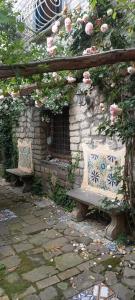 due panchine sedute davanti a un muro di pietra con rose di L'Antica Dimora a Meta