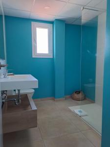 een badkamer met blauwe muren, een wastafel en een douche bij Bamblue Boutique Apartments in Pineda de Mar