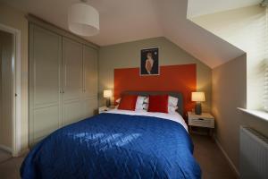 a bedroom with a blue bed with an orange headboard at Fairburn - DayDream Stays, luxury accomodation for holidays and contractors in Fairburn