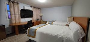 a hotel room with two beds and a desk at Niagara Inn in Niagara Falls