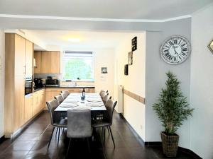 a dining room with a table and a clock on a wall at Ferienhaus Lorea Bütgenbach in Butgenbach