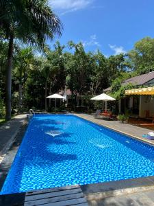 una gran piscina azul con 2 sombrillas en Have Fun Phú Quốc en Phu Quoc