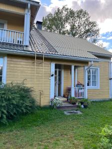 a yellow house with a porch and a balcony at Valkolan kartano, vanha tupa in Hankasalmi