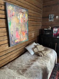 a bedroom with a bed and a painting on the wall at Valkolan kartano, vanha tupa in Hankasalmi