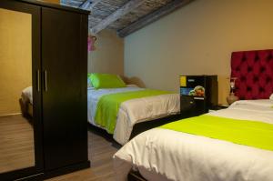 a bedroom with two beds with green and white sheets at Casa Suite Campana in Cuenca