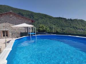 una grande piscina blu con ombrellone di Agriturismo La Vecchia Scuola a Villa Collemandina