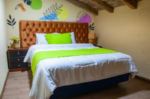a bedroom with a large bed with a green bedspread at Casa Suite Campana in Cuenca