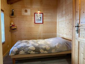 ein Schlafzimmer mit einem Bett in einer Holzwand in der Unterkunft La Grange à Coco avec jacuzzi in Bourg-Saint-Pierre