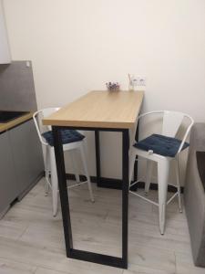 a wooden table and two white chairs in a kitchen at Небольшая, мега уютная квартира in Chişinău