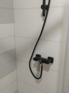 a shower with a hose attached to a white tile wall at Небольшая, мега уютная квартира in Chişinău