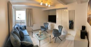 sala de estar con sofá azul y sillas en Haus Regina, en Timmendorfer Strand
