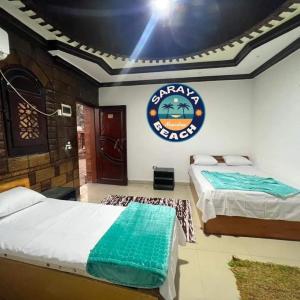2 Betten in einem Zimmer mit Schild an der Wand in der Unterkunft New Saraya Camp in Nuweiba