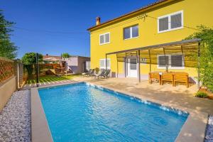 a swimming pool in front of a yellow house at House Leny by IstriaLux in Štokovci