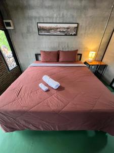 Una gran cama roja con dos toallas. en เป่าฟู่เฮ้าส์ Bao Fu's House en Chumphon