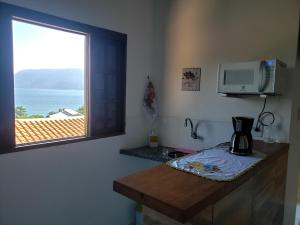 a kitchen with a window and a coffee maker on a counter at Chalé & Suítes Mar Aberto in Ilhabela