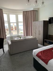 een slaapkamer met een bank, een bed en ramen bij Marsham Court Hotel in Bournemouth
