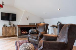 2 lederen stoelen in een woonkamer met een open haard bij Schwarzwaldhimmel in Feldberg