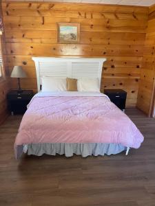 a bedroom with a large bed with a pink comforter at Mountain View Cabins in Wrightwood