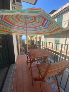 uma mesa e cadeiras com um guarda-sol numa varanda em Dimora Zefiro vacanze em Gioiosa Marea