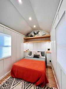 a bedroom with a bed with an orange blanket at The Endeavor Tiny Home! in Elizabethtown