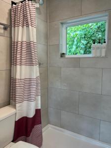 La salle de bains est pourvue d'un rideau de douche et d'une fenêtre. dans l'établissement The Tiny Getaway Home, à Elizabethtown